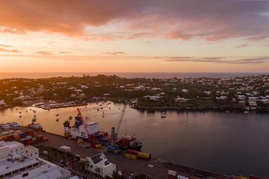 quai d'un port insulaire avec cargo amarré et grues de chargement au petit matin, ciel dégagé