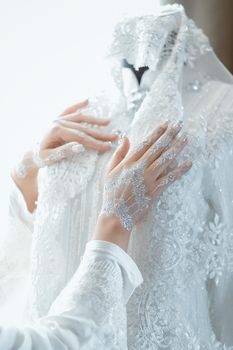 gros plan sur des mains expertes traitant délicatement une tache sur le tissu en dentelle d'une robe de mariée blanche