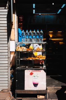 étal de street food mauricien au Central Market de Port-Louis avec dholl puri empilés et bouteilles de sirop colorées, lumière du matin filtrant à travers la structure métallique
