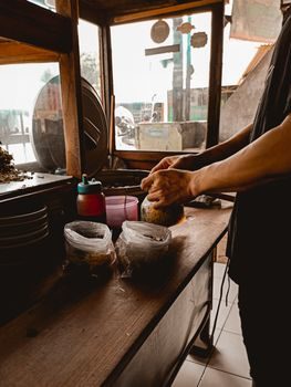 vendeur de rue mauricien préparant des dholl puri sur une tawa en fonte noire fumante, étal de sauces et d'achards posé à côté, ambiance de marché en fin de matinée