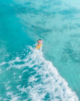 surfeur confirmé prenant une vague creuse sur un récif corallien au large d'une côte tropicale, eau turquoise, lumière de fin d'après-midi
